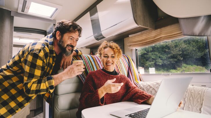 A couple checking out the online community on a computer in their RV