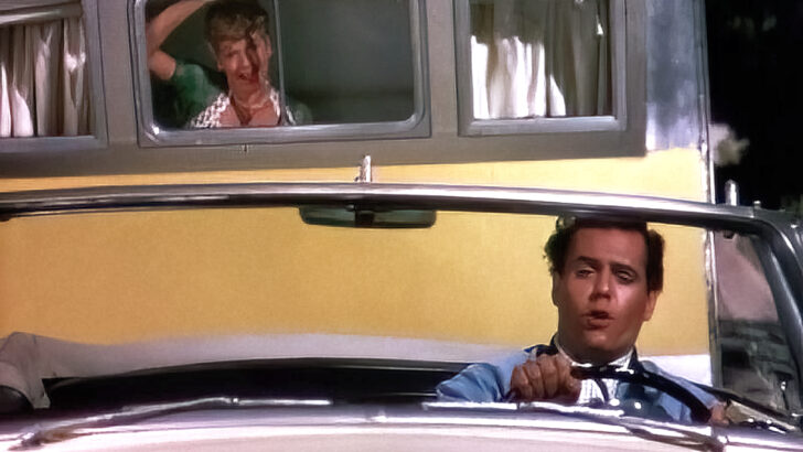 Lucy Ricardo riding in a travel trailer as it's being towed by a convertible driven by Ricky Ricardo
