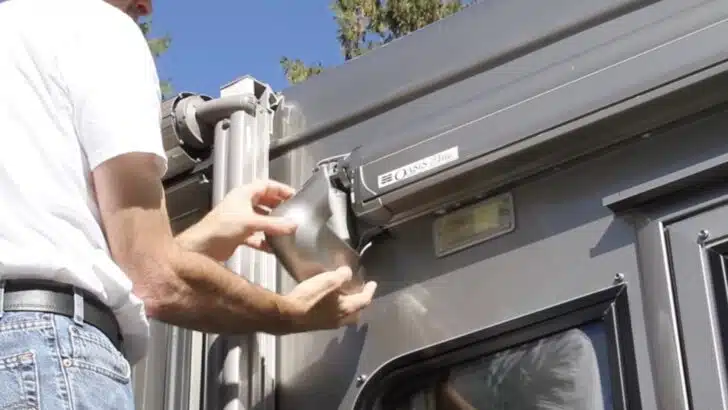 Removing the front part of the motor cover during a Dometic Oasis Elite door awning motor repair/replacement.