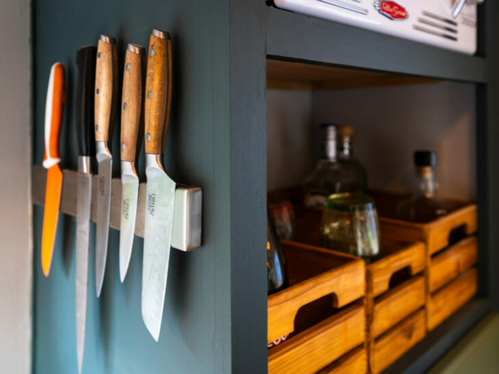 A magnetic knife rack mounted to the side of a storage shelf
