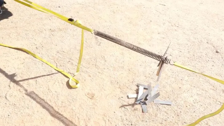 Using two vehicles to pull apart the coils of a spring