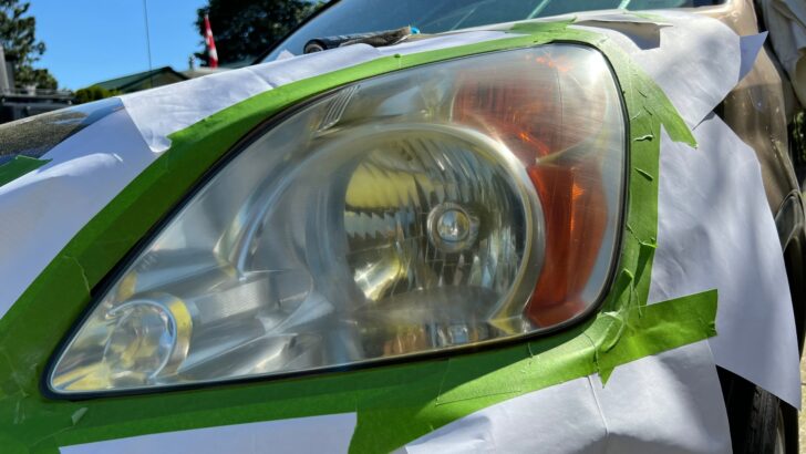 Masking tape and paper isolating the headlight from the vehicle's paint