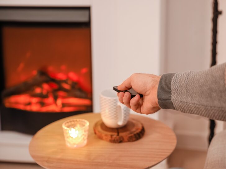 Someone using a remote to control an electric fireplace