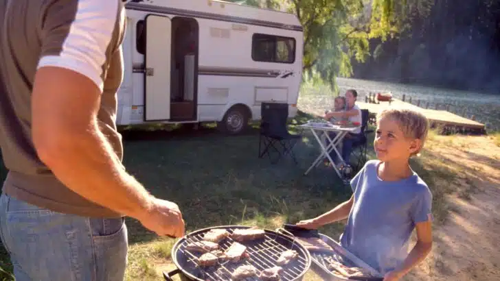 A man and a child preparing food at a campsite